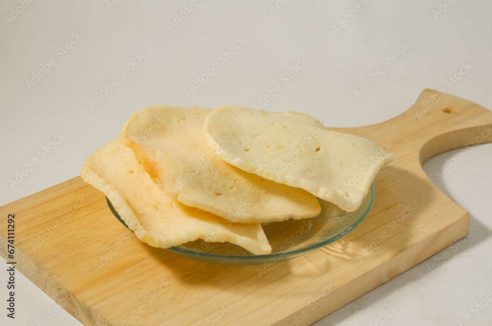 Three shrimp crackers are served on a small plate on a wooden board isolated on a white background Three shrimp crackers are served on a small plate on a wooden board isolated on a white background