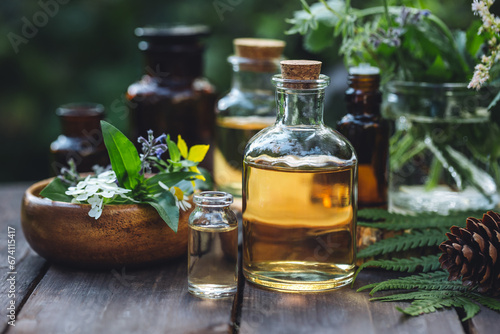 Herbal pure natural cosmetic ingredients on wooden background. Mix of holistic flowers and herbs, salt, massage herb-infused essential oil in glass bottles. Aromatherapy, fragrance production
