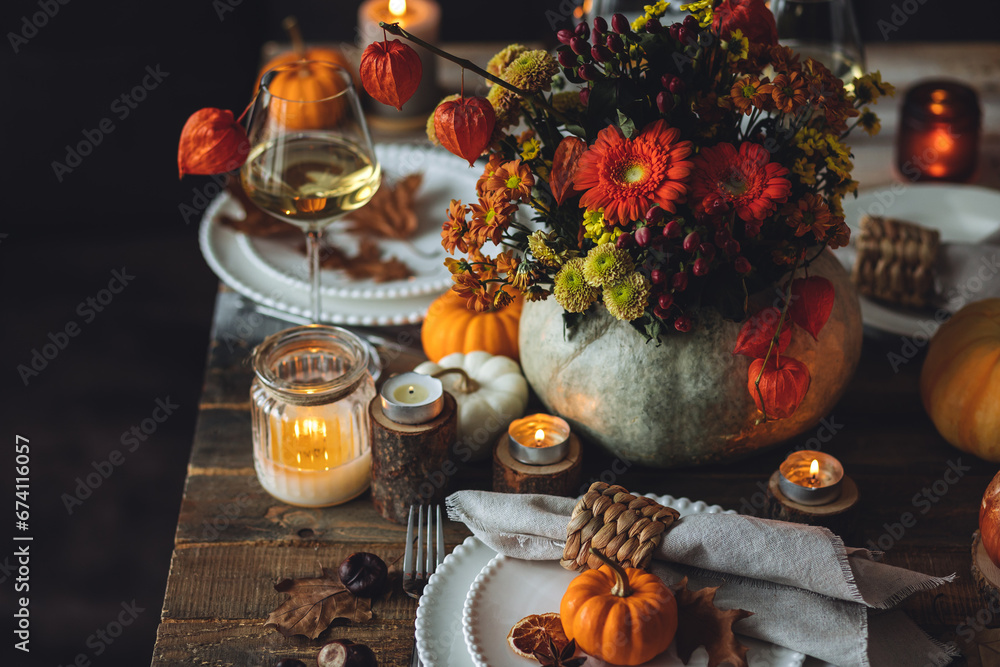 Fototapeta premium Fall composition. Orange pumpkins, flowers and candles on wooden table. Family elegant Thanksgiving or halloween dinner. Cozy autumn concept, simple handmade decoration, countryside style, wine