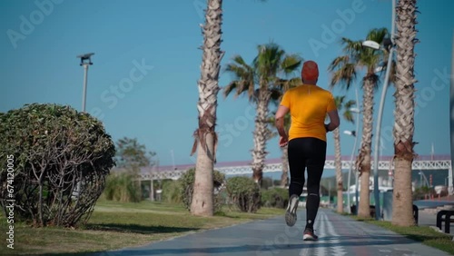 Thick man does running jogging workout sunny morning, outside street, urban palm marathon. Healthy lifestyle for middle aged adults, losing weight, burning fat, fitness training photo
