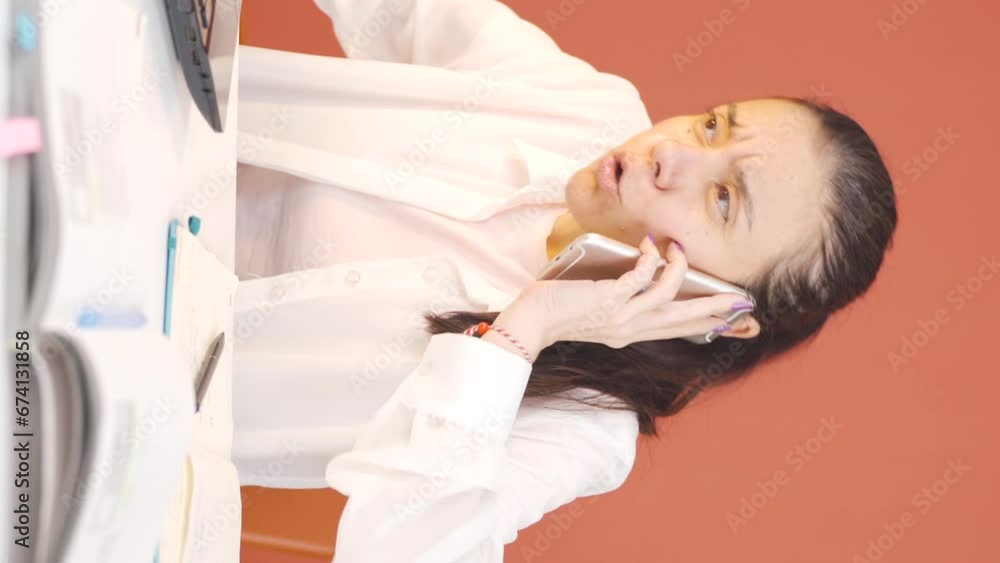 Vertical video of Woman using laptop nervously talking on the phone. Vertical video of Woman using laptop nervously talking on the phone.