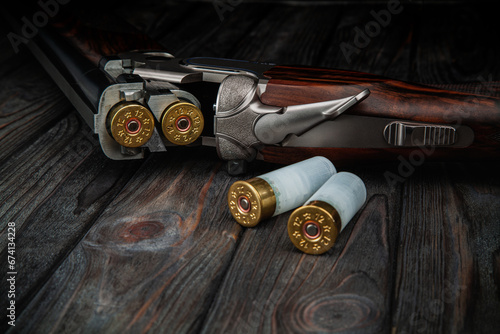Classic trigger double-barreled hunting rifle on a wooden background. Concept postcards for hunters. Smooth-bore hunting rifle open for reloading.