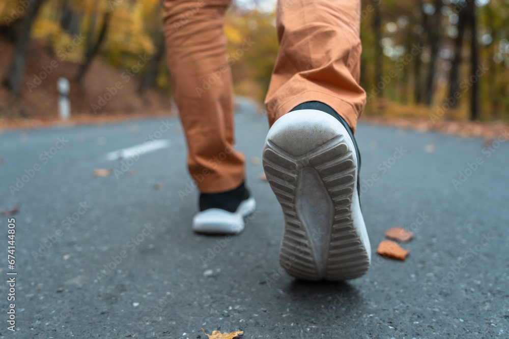 A man walks on an asphalt road