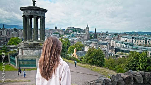 Beautiful woman enjoying amazing view of Dugald Stewart Monument in Edinburgh, Scotland.Tourist girl visit Edinburgh city. photo