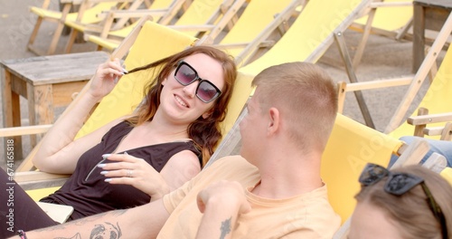 Girl touching her hair during conversation. Repeatedly touches or plays with her hair, these actions can be considered intrusive or compulsive gesture convey various emotions or psychological states. photo