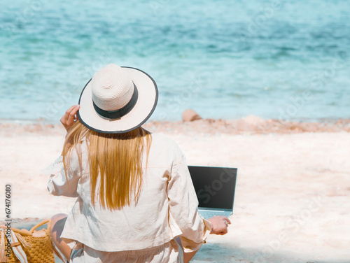 Obraz na płótnie young woman uses laptop computer on the beach. distance work, freelancer and blogger concept. WiFi unlimited w salonie