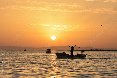 Fishing boat on a sea at sunset. A fisherman spread his arms wide