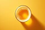 Top view of a light beer glass with shadow on yellow background