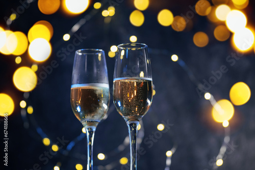 Two glasses of sparkling champagne on a Christmas background with a garland of bokeh