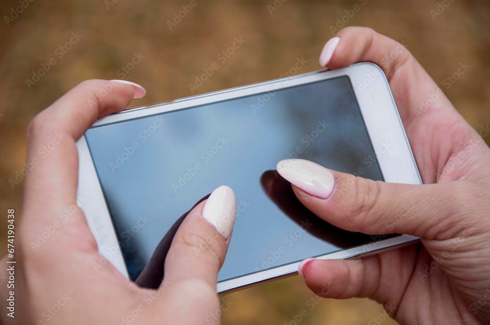 Close up view of female hand with long nails typing text message outdoors Close up view of female hand with long nails typing text message outdoors
