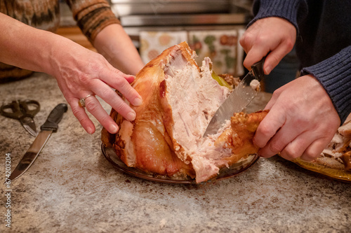Family preparing turkey for Thanksgiving dinner. Person cutting big turkey 