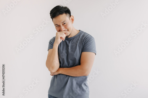 Shy and embarrassment funny asian man in blue t-shirt isolated on white wall.