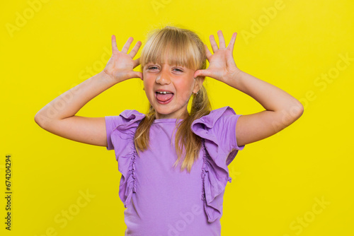 Slika na platnu Cheerful funny bully young cute girl showing tongue making faces at camera, fooling around, joking, aping with silly face, teasing