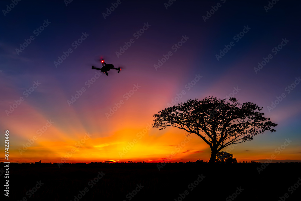 Minimal Flying drone  over  cloud sunset sky background with dark tree.