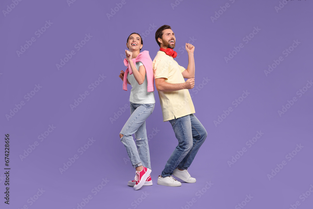 Happy couple dancing together on violet background Happy couple dancing together on violet background