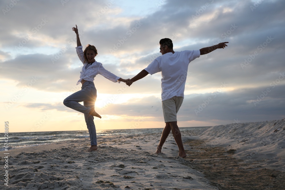 Fototapeta premium Happy couple dancing on beach at sunset