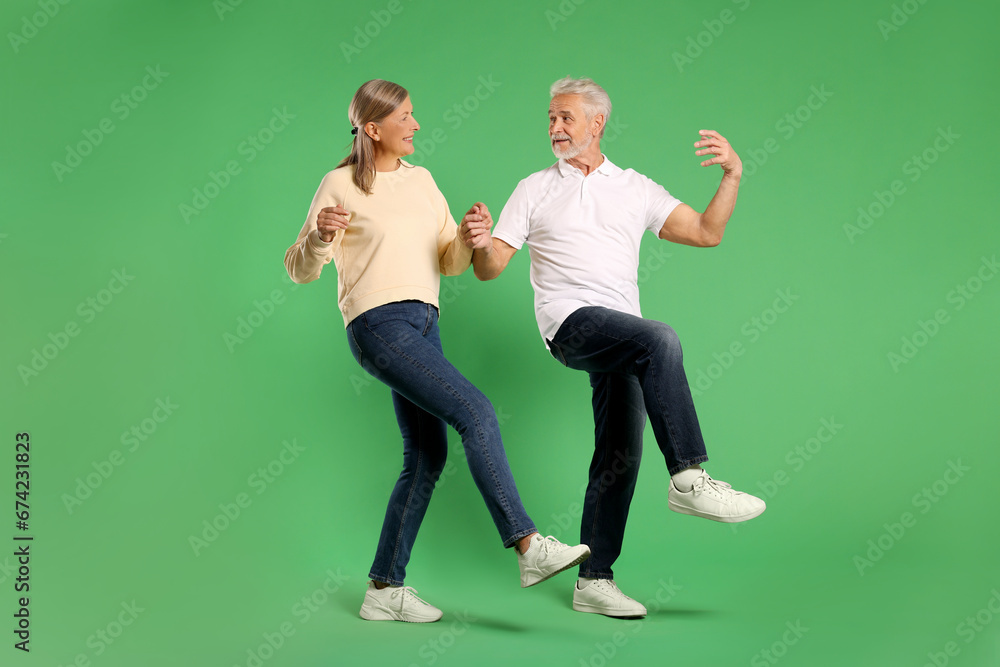 Senior couple dancing together on green background Senior couple dancing together on green background