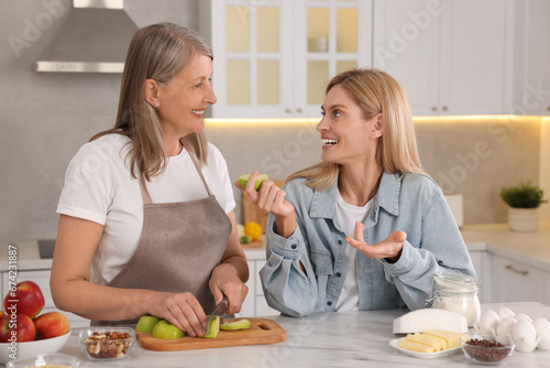Happy mature mother and her daughter in kitchen