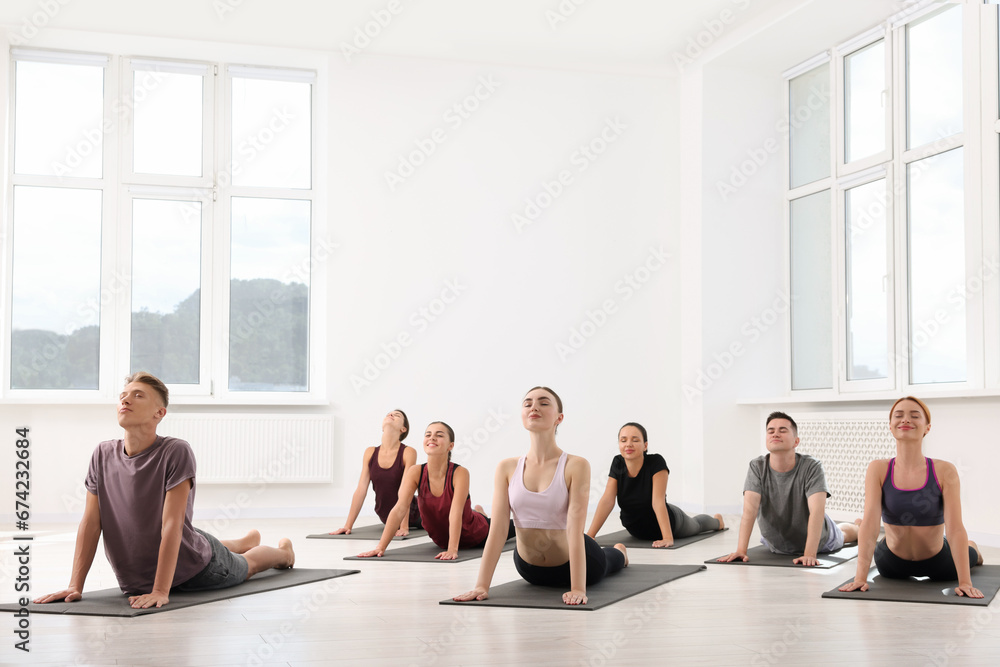 Group of people practicing yoga on mats indoors, space for text Group of people practicing yoga on mats indoors, space for text
