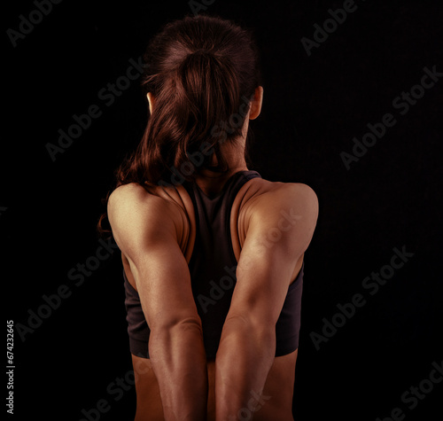 Strong sporty woman doing the arms and shoulders stretching exercise holding the hands in fist behind the back to relaxing back side of body in sport wear. Sports exercising.