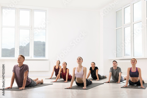 Group of people practicing yoga on mats indoors, space for text