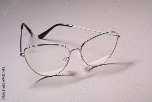 Stylish pair of glasses with metal frame on light background, closeup