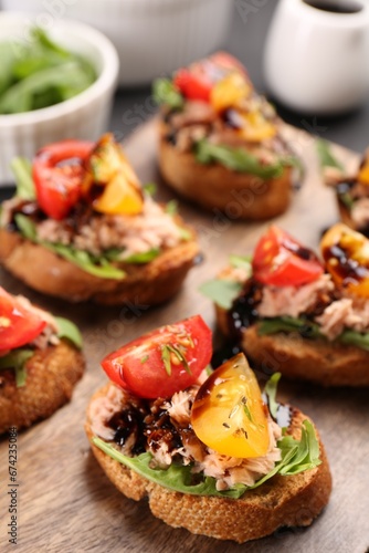 Delicious bruschettas with balsamic vinegar, tomatoes, arugula and tuna on table