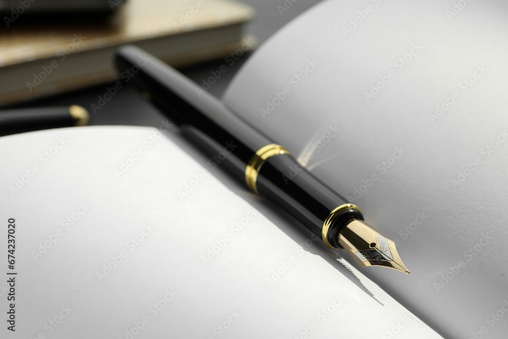 Stylish black fountain pen on open notebook, closeup Stylish black fountain pen on open notebook, closeup