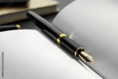 Stylish black fountain pen on open notebook, closeup