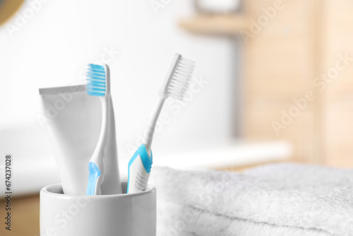 Plastic toothbrushes  toothpaste and towels on blurred background  closeup. Space for text