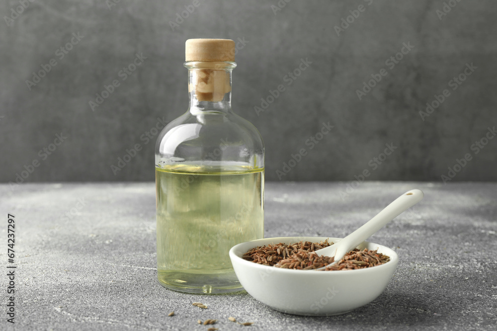 Caraway (Persian cumin) seeds in bowl and essential oil on light gray textured table Caraway (Persian cumin) seeds in bowl and essential oil on light gray textured table