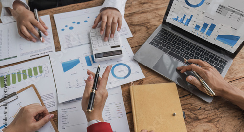 Business People Meeting using laptop computer,calculator,notebook,stock market chart paper for analysis Plans to improve quality next month. Conference Discussion Corporate Concept