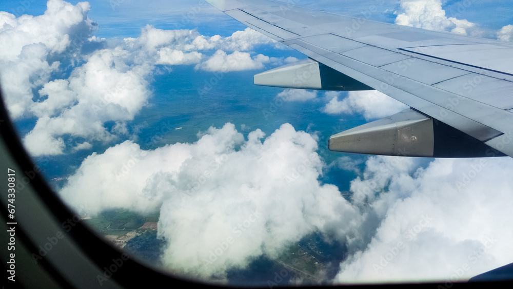 Fototapeta premium Aerial view of sky and clouds through an airplane window. Travel concept. traveler, trip, vacation, tourism, landscape, vibrant, nature, scenery, background