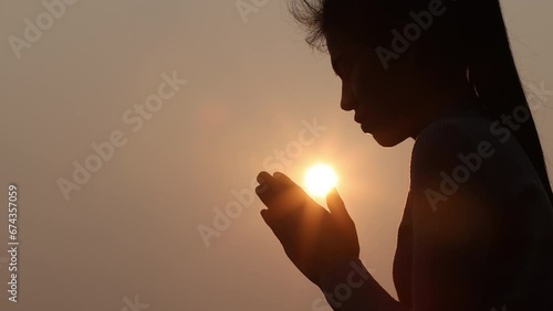 Silhouette of young human hands praying to god at sunrise, Christian Religion concept background. photo