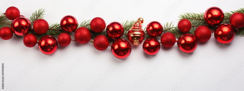 A horizontal line of red Christmas ornaments are neatly arranged on a pine branch against a pure white background. A horizontal line of red Christmas ornaments are neatly arranged on a pine branch against a pure white background.