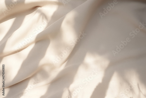 Closeup of crumpled beige silk fabric with natural light with shadow from window. High quality photo