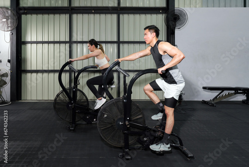 Fitness Couple Cycling on Stationary Bikes in Health Club