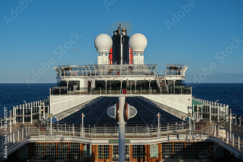 Classic luxury ocean cruiseship cruise ship liner with red and black funnel at sea with partial view of outdoor decks, funnel, superstructure photo
