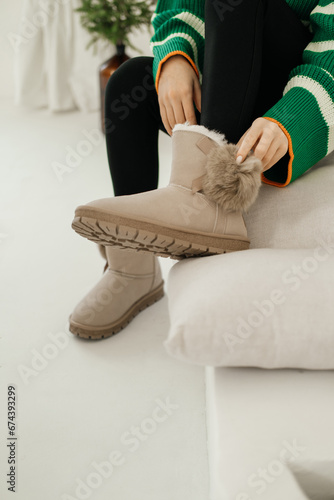 Beige winter boots. Women's legs close-up. A woman in beige winter boots. Ugg boots.