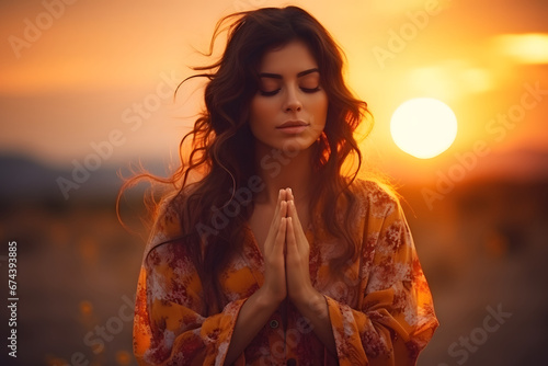 Woman on her knees praying to god at sunset