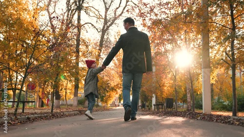 Loving father takes leisurely stroll through public garden with adorable daughter photo