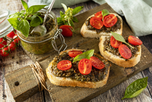 Traditional italian appetizer or snack, antipasto. Homemade bruschetta with pesto sauce, fresh tomatoes on a wood background.