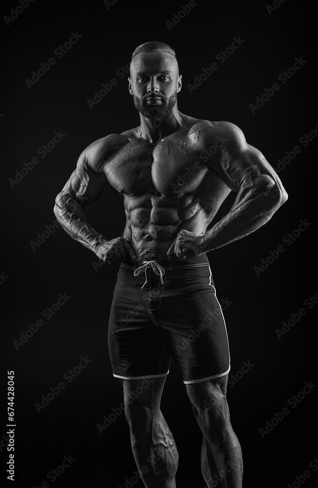 Silhouette of a strong bodybuilder. Confident young fitness athlete with a powerful body and perfect abs. Black and white photography. Dramatic light. Silhouette of a strong bodybuilder. Confident young fitness athlete with a powerful body and perfect abs. Black and white photography. Dramatic light.