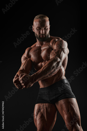 Handsome strong athletic men pumping up muscles. Workout, bodybuilding concept. Black background. © andy_gin
