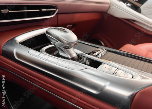Automatic gear stick of a modern car. Modern car interior details. Close up view. Car inside. Automatic transmission lever shift. Red leather interior with stitching