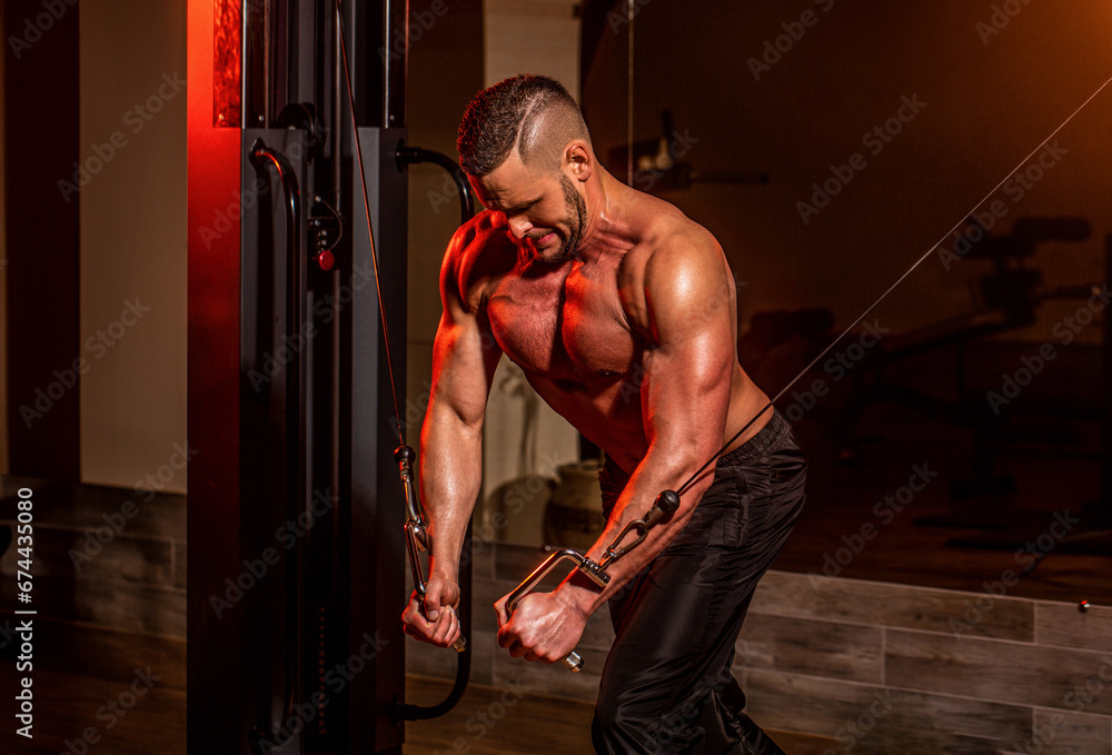 Handsome man with big muscles in gym. Sportman in the gym. Abs and biceps. Fitness man execute exercise with exercise-machine Cable Crossover in gym - obrazy, fototapety, plakaty 