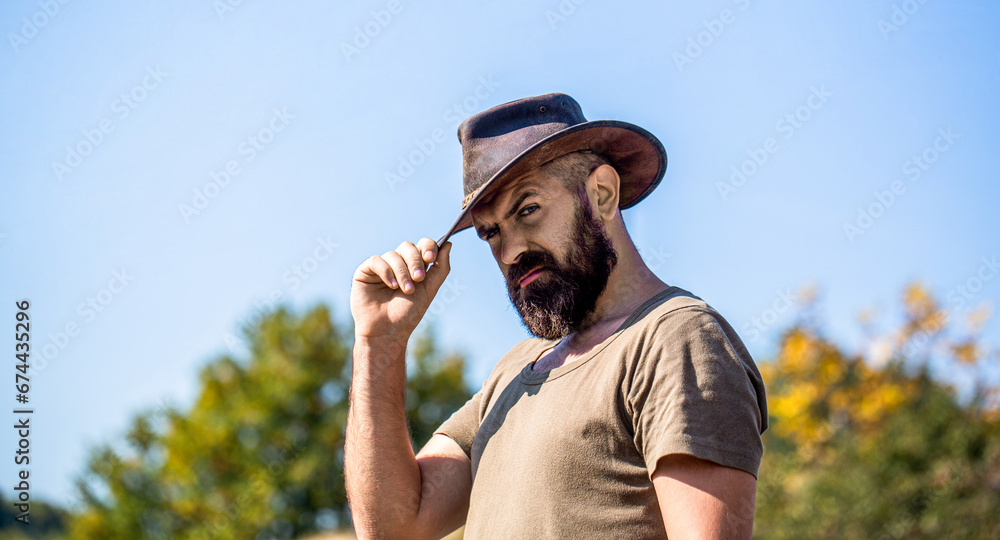 Obraz premium Cowboy Hat. Portrait of young man wearing cowboy hat. Cowboys in hat. Handsome bearded macho. Man unshaven cowboys
