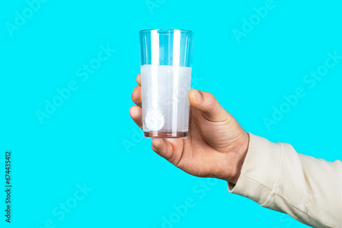 Glass of water tablet. Glass with effervescent tablet in water with bubbles. White pill and a glass of water in man hands. Health concept. Close up of man holding a pill photo