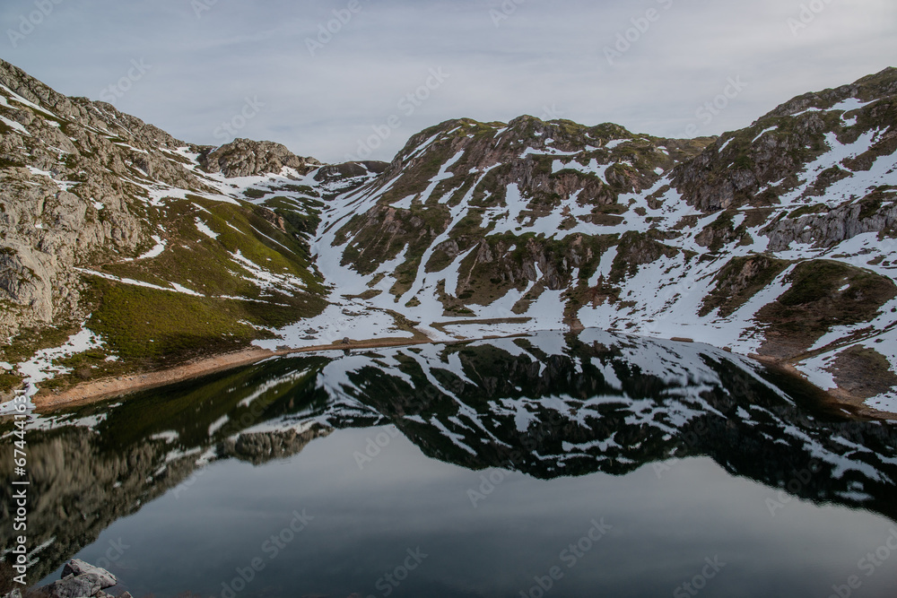 high mountain lake next to the snow that has fallen on the mountainside