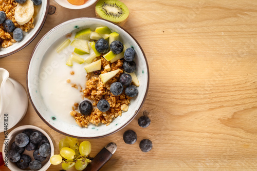 Weight loss, healthy lifestyle and eating. Healthy breakfast bowl with ingredients granola fruits Greek yogurt and berries on wooden table with copy space top view